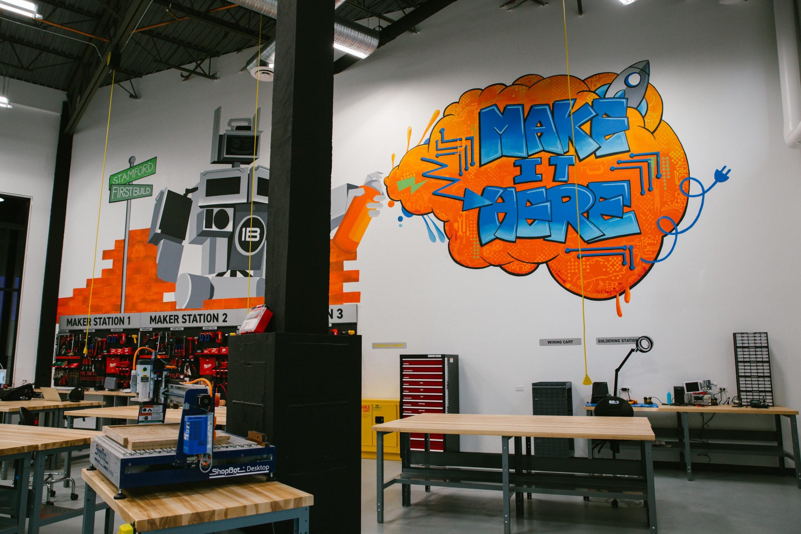 FirstBuild at CoCreate Make It Here graffiti sign with tools in the background